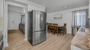 Een moderne keuken met een roestvrijstalen koelkast, een houten eettafel en stoelen.