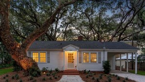 A single-story house with a front porch, a covered entryway, and a gravel driveway. - House is close to Beach Pier, Shops & Restaurants (Saint Simons Island)