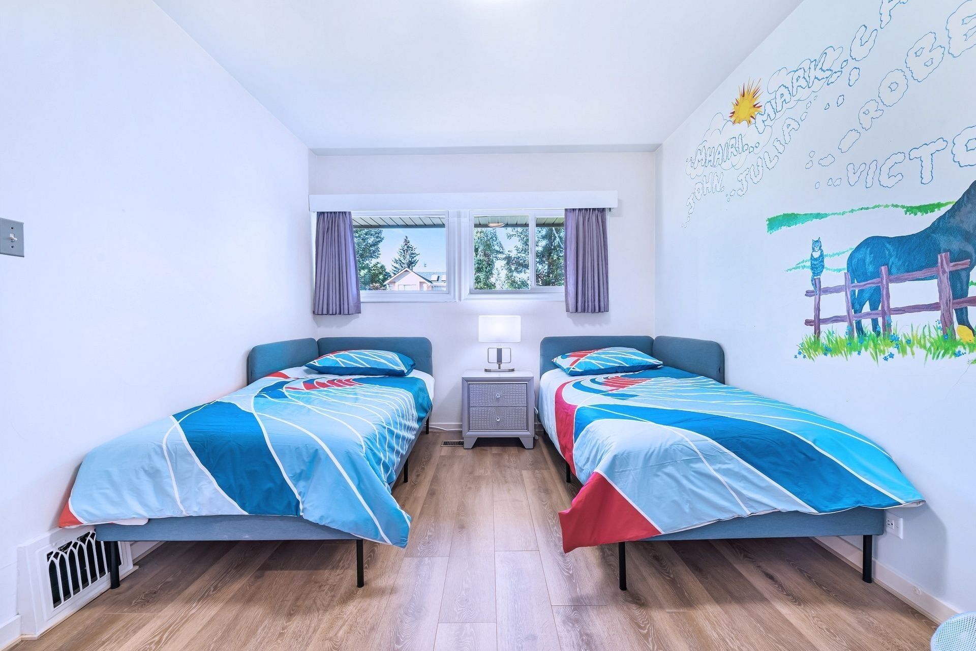 A room with two beds, a window with curtains, a radiator, and a wall mural.