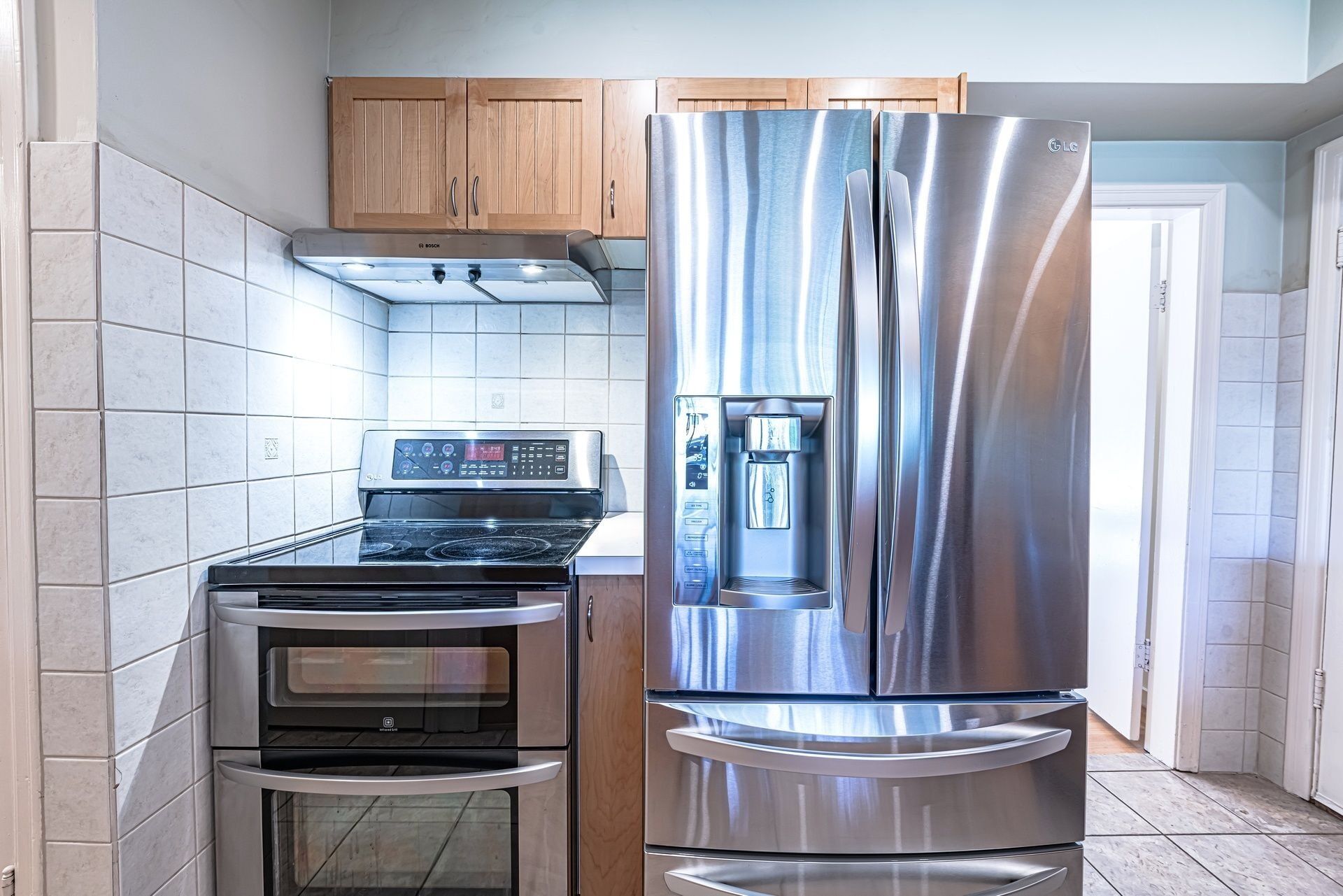 A kitchen with a stainless steel refrigerator, a built-in oven, and a stovetop.