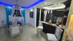 A modern kitchen with dark cabinets, a white countertop, and a hanging light fixture.