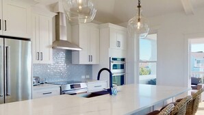 A modern kitchen with white cabinets, stainless steel appliances, and a marble island.