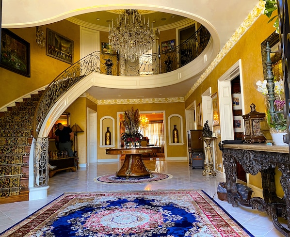 Un vestíbulo imponente con una escalera en espiral, un candelabro y una decoración elaborada.