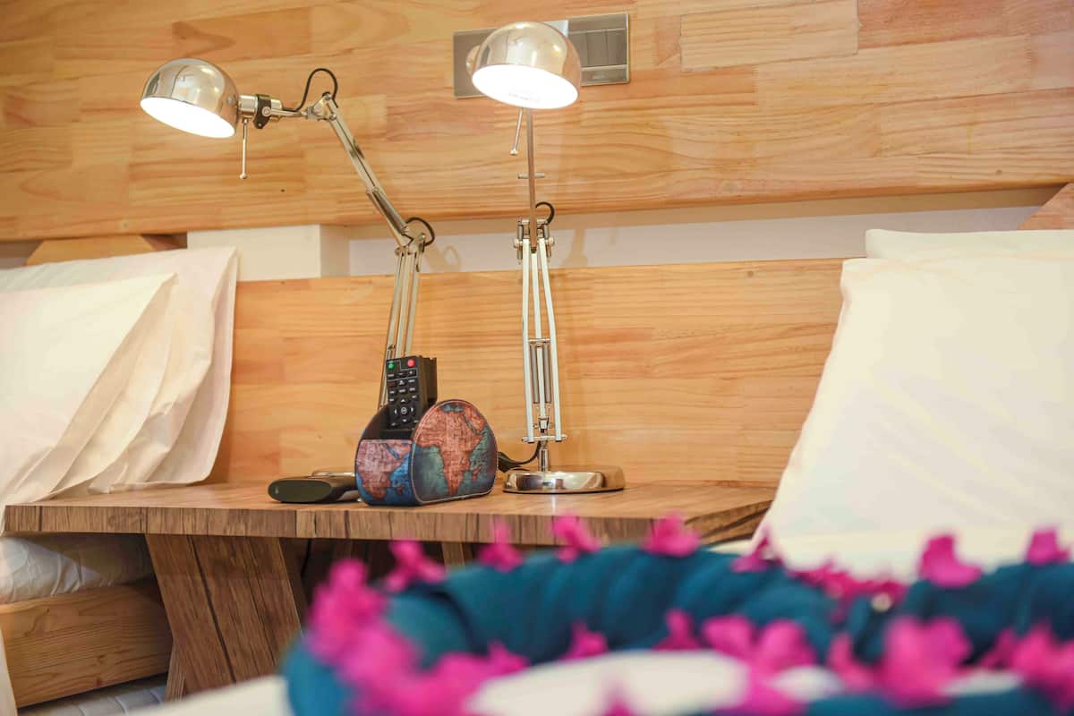 A wooden bedside table with two desk lamps, a globe, and a remote control.