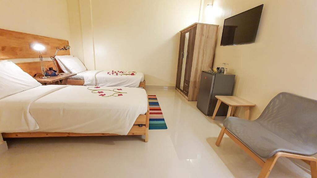 A bedroom with two beds, a desk, a chair, a wardrobe, and a TV.
