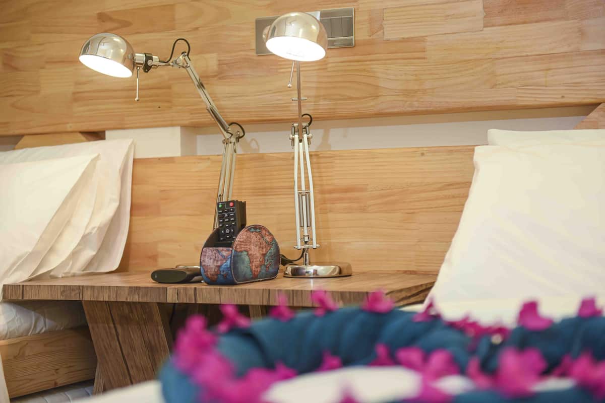 A wooden bedside table with two desk lamps, a globe, and a remote control.