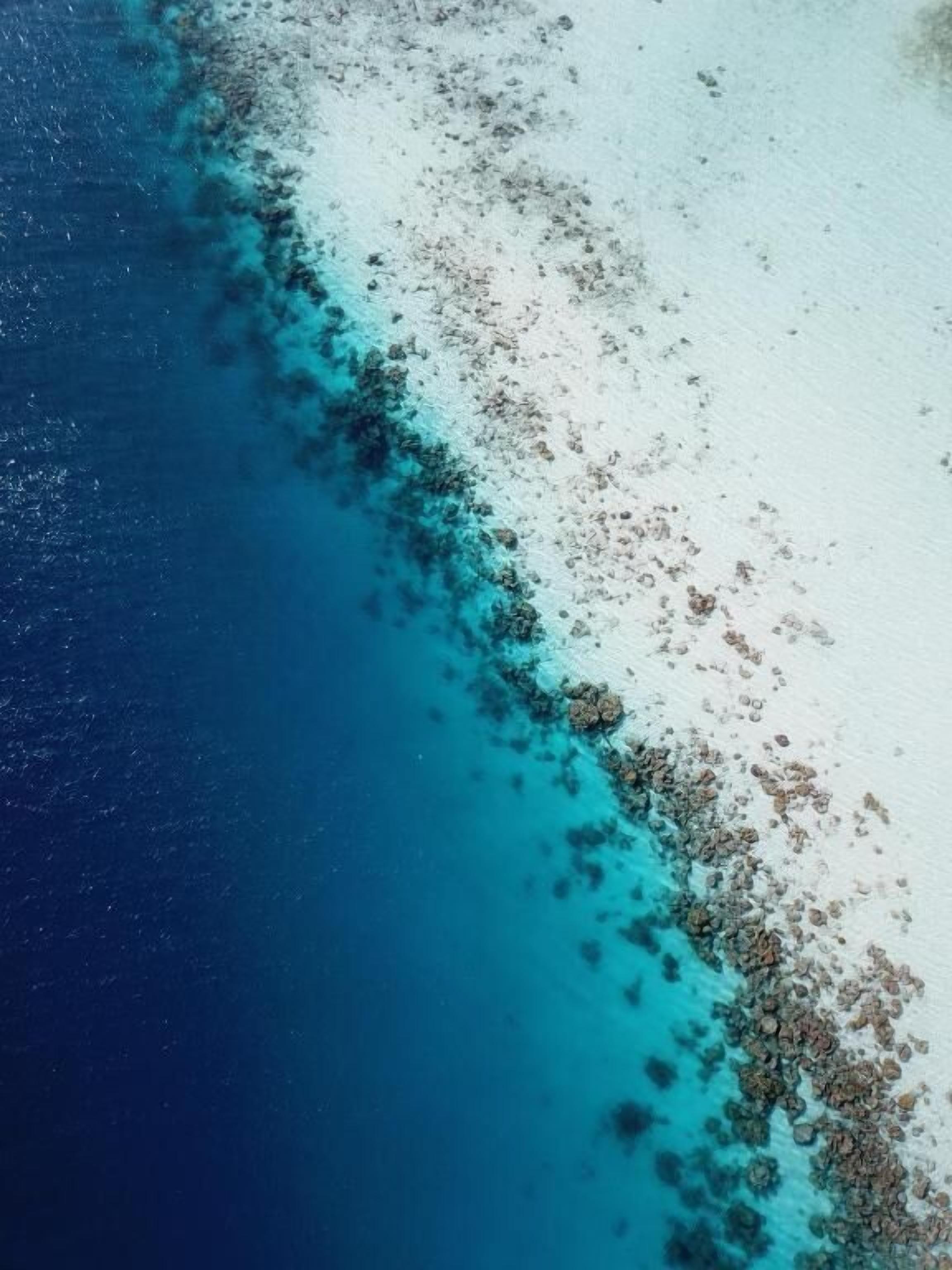 Vista aèria d'una platja amb aigües turqueses cristal·lines i sorra blanca.