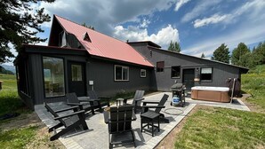 A modern house with a patio area featuring outdoor furniture and a hot tub. - Hidden Gem, Hot tub, Garage, Amazing Views! (Mt. Crested Butte)