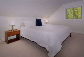 Ein Schlafzimmer mit einem Einzelbett, zwei Nachttischen und einem Fenster.