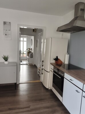 A modern kitchen with a stainless steel range hood, a built-in oven, and a wooden countertop. - Sartorius Vacation Apartment, Vacation Apartment at Hemsberg (Bensheim)