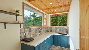A modern kitchen with blue cabinets, a tiled backsplash, and wooden ceiling beams. - Jomotel Dayaar (Theog)
