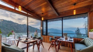 A dining area with wooden furniture and large windows offering a mountain view. - Jomotel Dayaar (Theog)