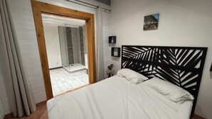 Un dormitorio con cama, ducha y puerta que da al baño.