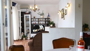 Un coin repas avec une table dressée pour deux personnes, un lustre et un téléviseur en arrière-plan.