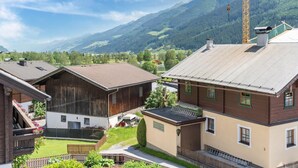 Ein ländliches Dorf mit traditionellen Holzhäusern, einem Baukran und einer Bergkulisse.