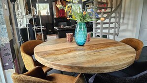 A round wooden table with a blue vase and two patterned glass cups, surrounded by two brown chairs. - Atelier House With hot tub (Sleen)