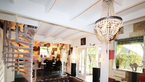 A cozy living room with a brown leather sofa, a chandelier, and a spiral staircase. - Atelier House With hot tub (Sleen)