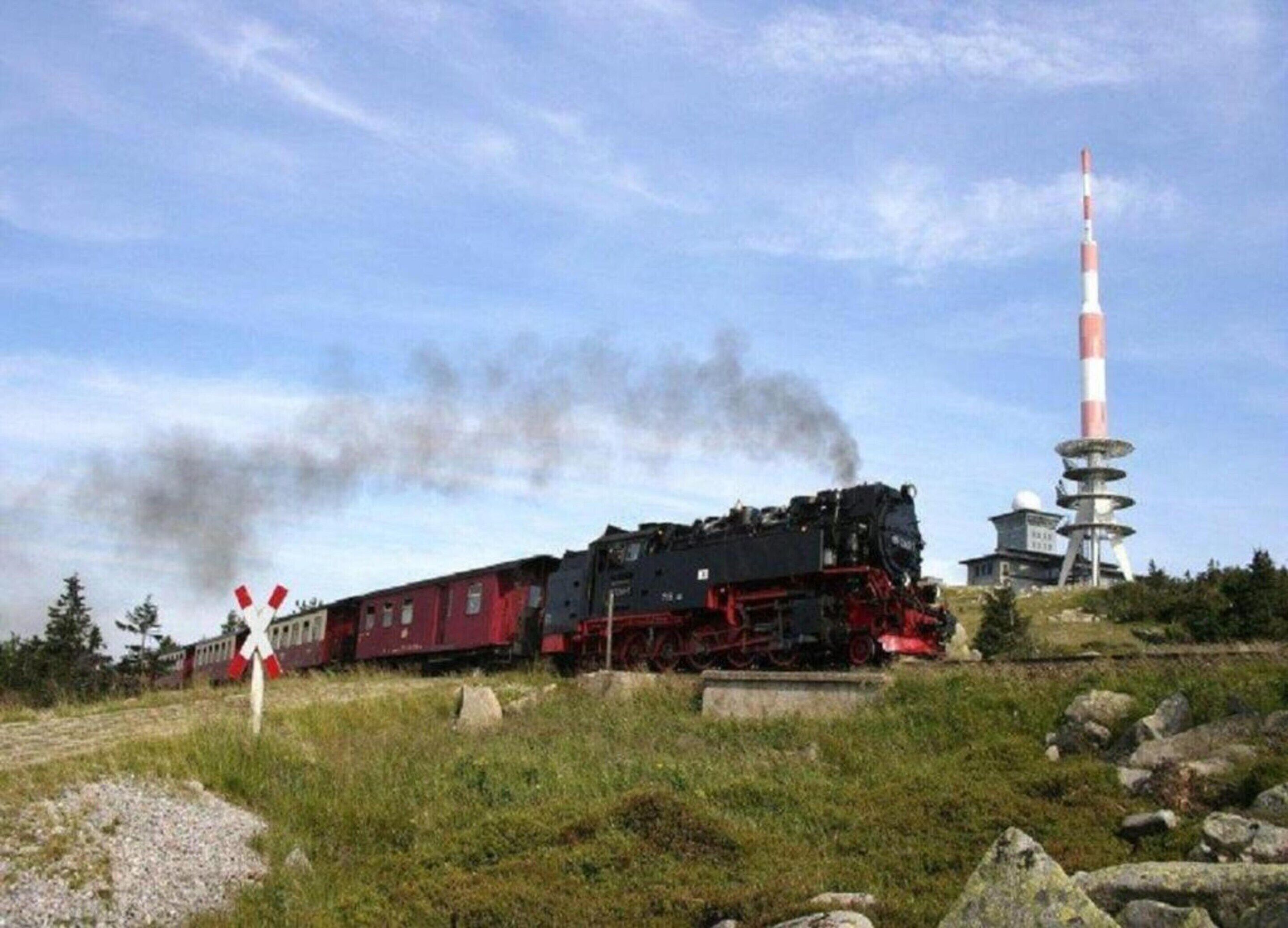 A steam locomotive with a tall, striped tower in the background.