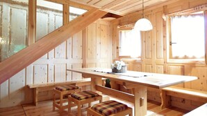 A wooden cabin interior with a dining table, benches, and a staircase. - Belvilla by OYO Hilltop Chalet in Lamon With Views (Lamon)