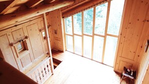 A wooden cabin interior with a large window, wooden walls, and a staircase. - Belvilla by OYO Hilltop Chalet in Lamon With Views (Lamon)