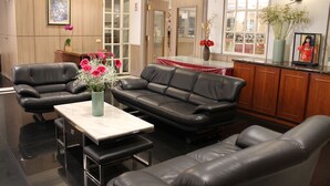 A modern living room with leather sofas, a glass coffee table, and a vase of flowers. - Hermes Hotel (Hsinchu)