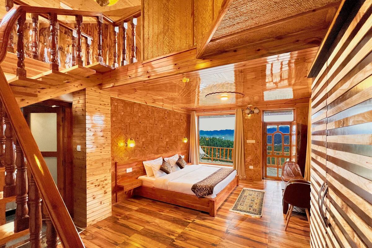 Interior de madera con una cama, una escalera y una vista por la ventana.