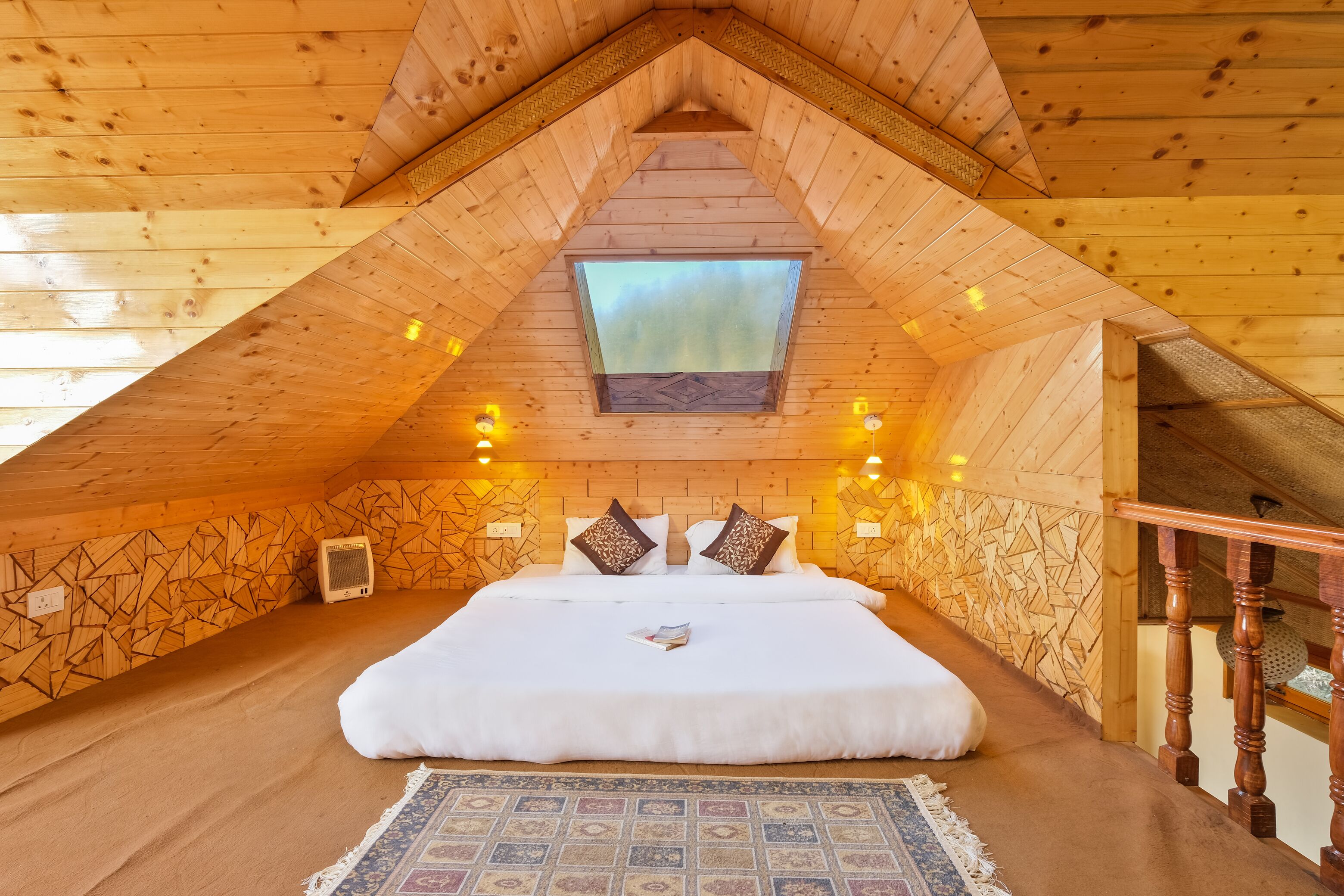 A cozy attic bedroom with a large bed, a skylight, and wooden walls.