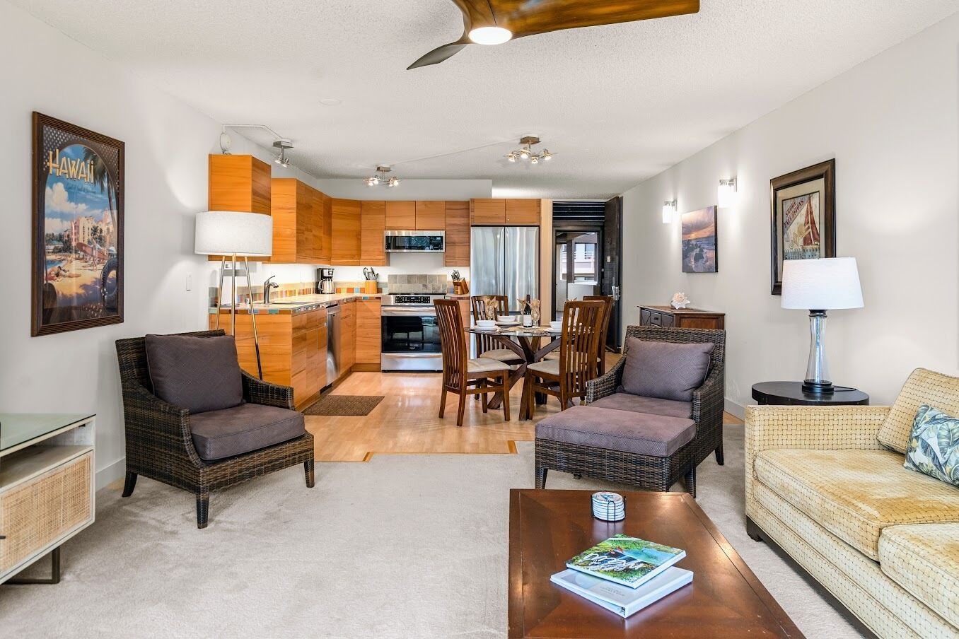 A modern living room with wicker furniture, a dining area, and a kitchen with wooden cabinets.