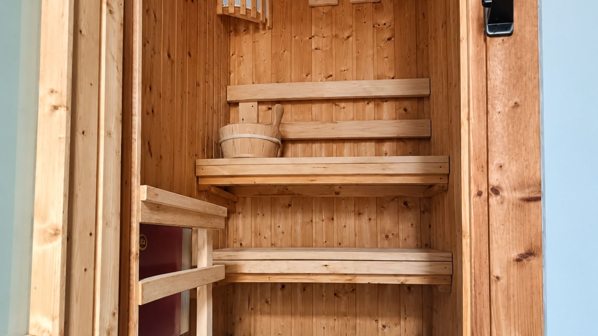 A wooden sauna with multiple benches and a central heating element.