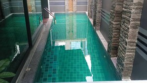 Ein Innenpool mit klarem Wasser, umgeben von Steinwänden und einem gefliesten Boden.