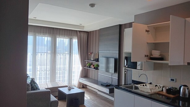 Eine moderne Küche mit Einbauofen, Mikrowelle und Spüle. Ein Essbereich mit Tisch und Stühlen sowie ein großes Fenster mit Vorhängen vorhanden.