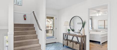A staircase leading to a bedroom with a bed, a console table with a lamp, and a mirror.