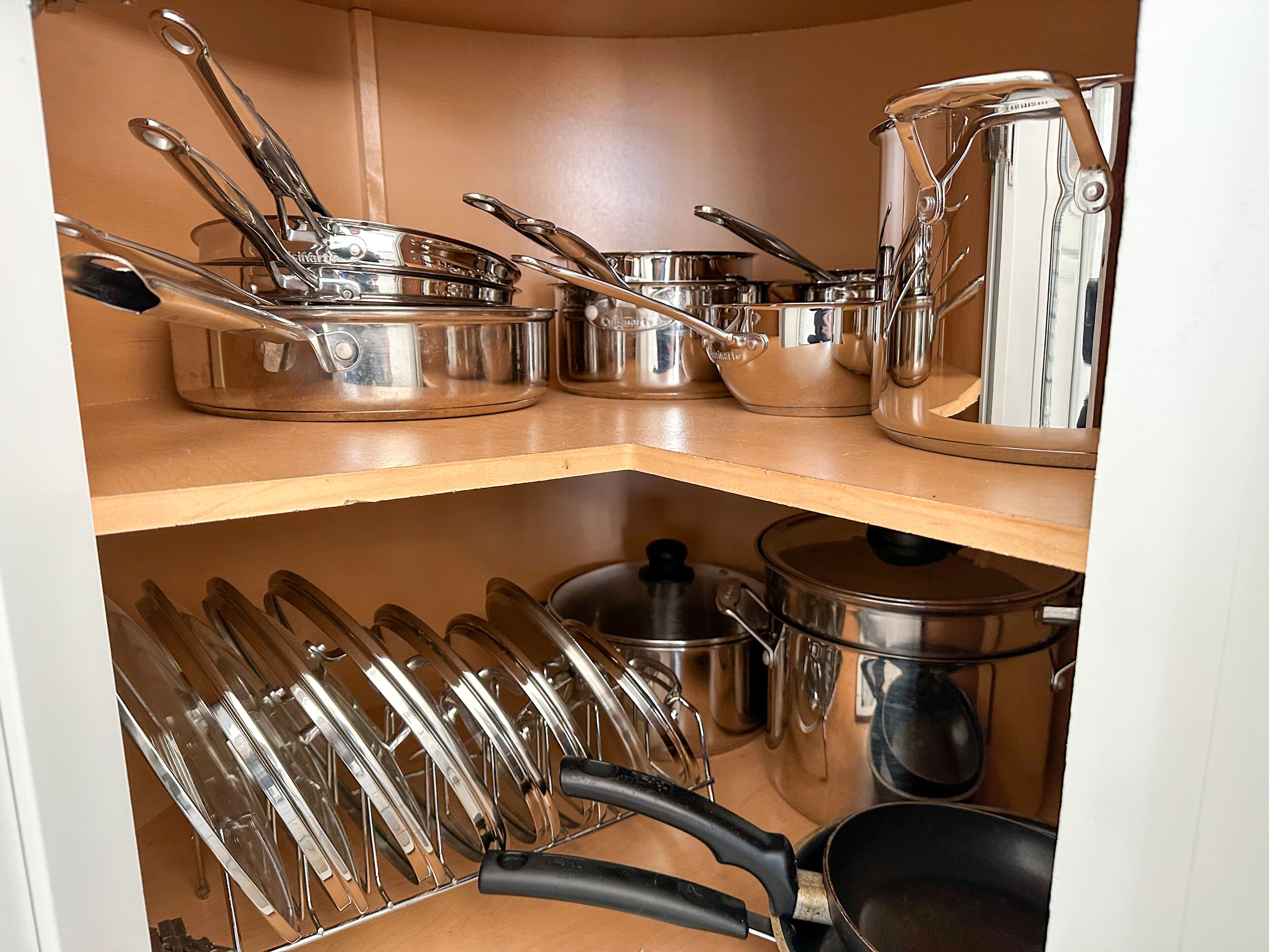 A kitchen with stainless steel cookware and utensils on shelves.
