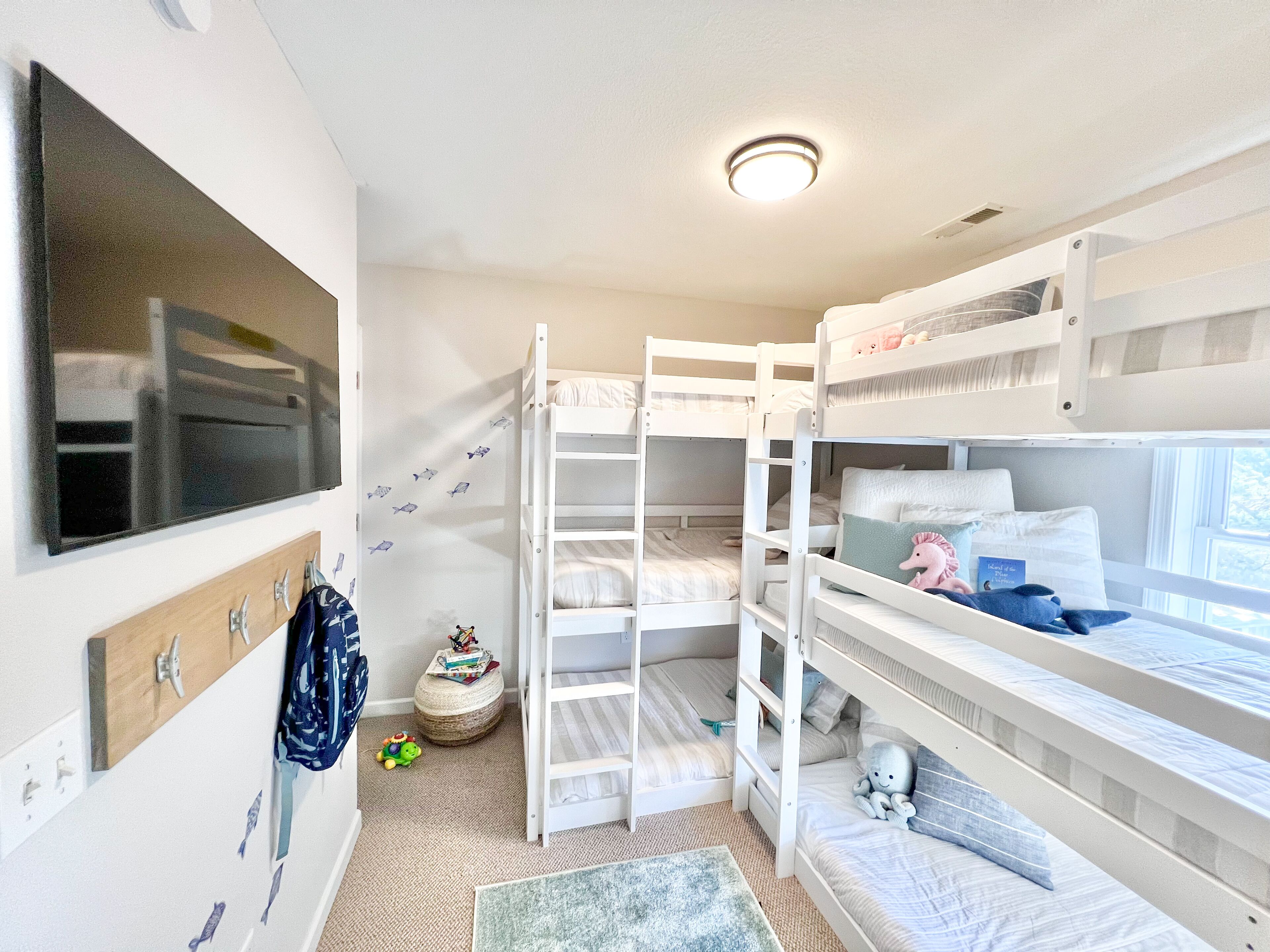 A bunk bed room with a flat-screen TV, a small round table, and a window.