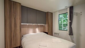 Un dormitorio con cama, armario de madera y ventana con cortinas.