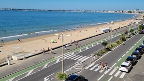 Eine Küstenstraße mit Strand auf einer Seite und geparkten Autos auf der anderen.