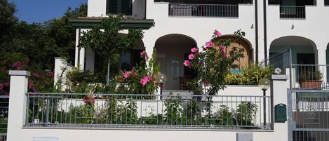 A two-story building with a balcony, arched windows, and a gated entrance.