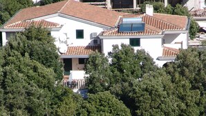 A residential building with a tiled roof, surrounded by dense greenery.