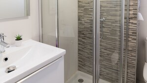 A bathroom with a white sink, a small potted plant, and a glass-enclosed shower with a tiled wall. - Spacious & Renovated 2BR Apt with Parking, Near Calle Laurel, Logroño (Logroño)