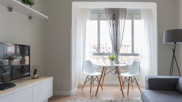 A modern living room with a flat-screen TV, a grey sofa, a dining table with two chairs, and a large window with curtains. - Spacious & Renovated 2BR Apt with Parking, Near Calle Laurel, Logroño (Logroño)