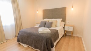 A modern bedroom with a large bed, bedside tables, and a headboard. - Spacious & Renovated 2BR Apt with Parking, Near Calle Laurel, Logroño (Logroño)