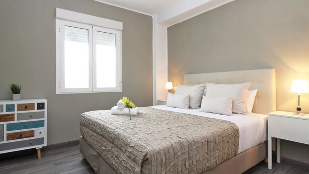 A bedroom with a bed, bedside tables, a dresser, and a window.