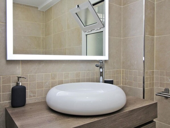 A bathroom with a large mirror, a round white sink, and a shower. - Bright apartment with terrace in central Malaga (Málaga)