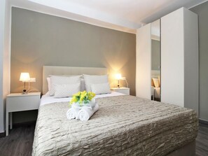 A hotel room with a large bed, two bedside tables with lamps, a mirror, and a bouquet of flowers on the bed. - Bright apartment with terrace in central Malaga (Málaga)