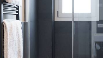 Ein modernes Badezimmer mit einer Duschkabine aus Glas, einer weißen Toilette und einem Handtuchhalter mit Handtüchern.