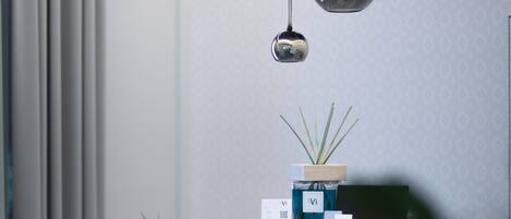 A modern reception desk with a potted plant, a wooden counter, and a sign. There are two chairs and a desk lamp.