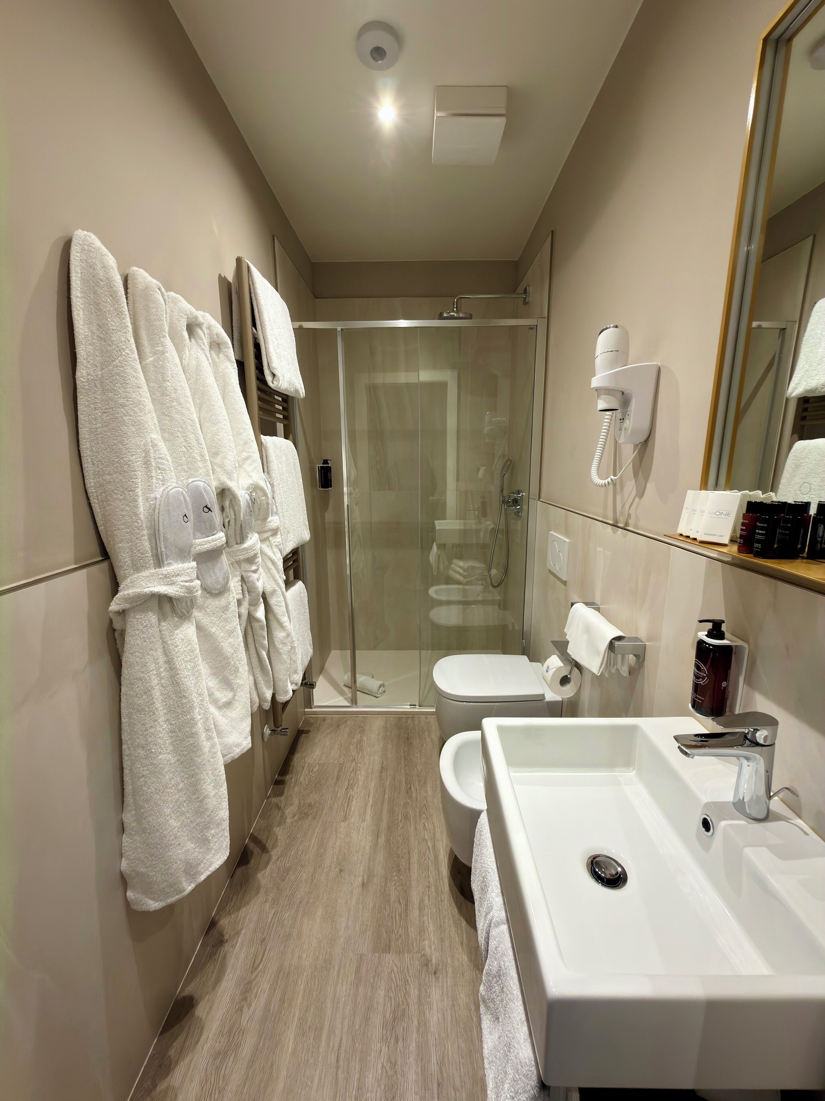 A modern bathroom with a glass-enclosed shower, a white sink, and a toilet.
