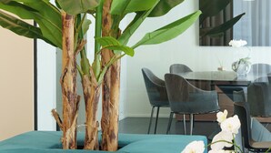 A modern room with a teal sofa, a glass table, and a large window. - VI SUITES (Viareggio)
