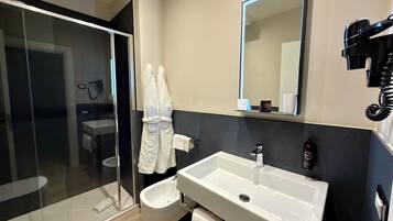 A modern bathroom with a glass shower enclosure, a white sink, and a large mirror.