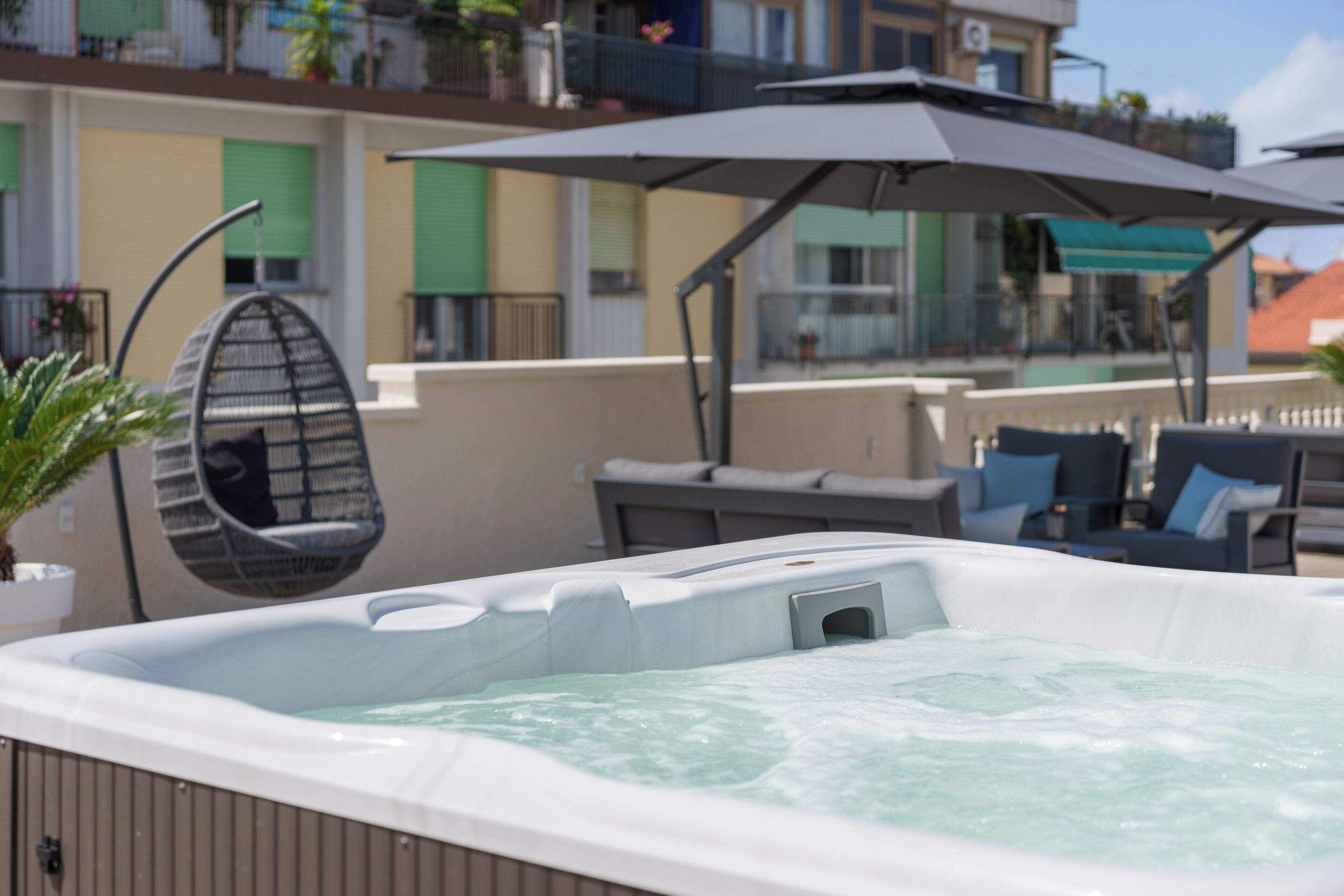 Un jacuzzi con dosel, una hamaca colgante y mobiliario de exterior.